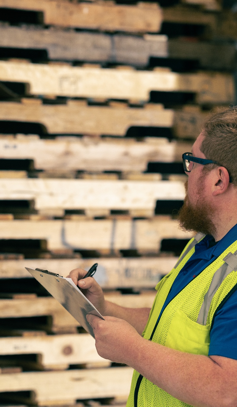 Man inspecting pallets with clipboard